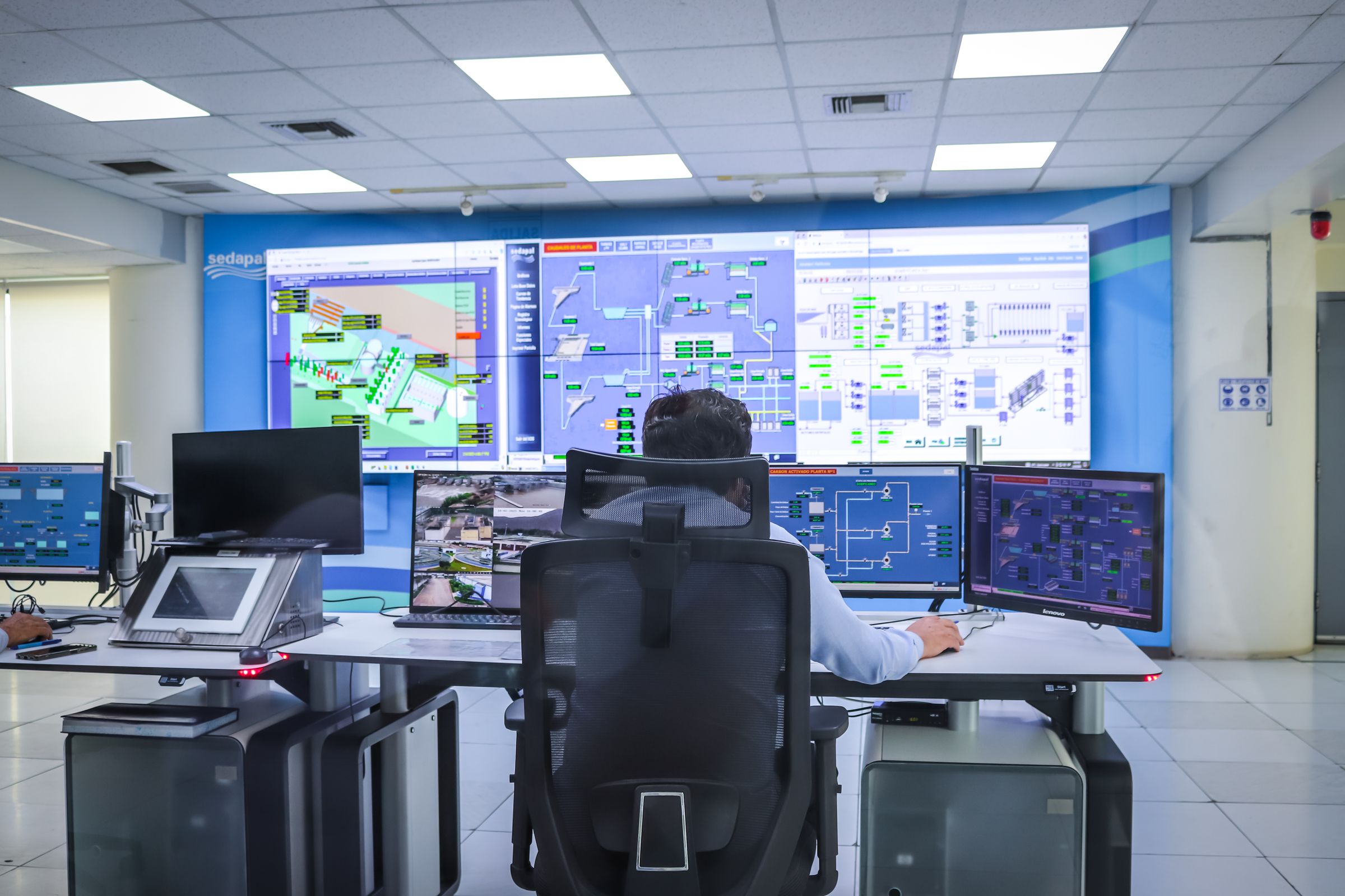 Operators in an industrial control room in front of large screens